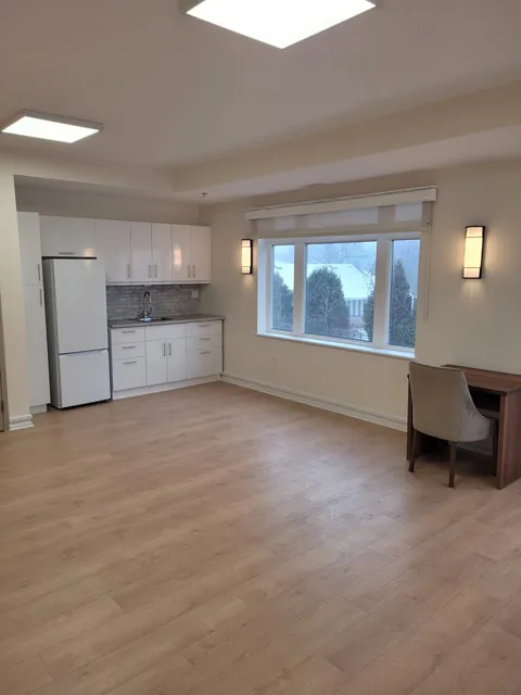Unfurnished suite with a kitchenette and large windows.
