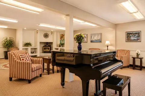 Lounge with upholstered seating, a grand piano, plants and wall artwork.