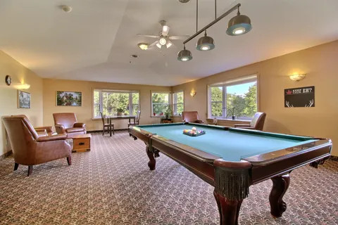 Billiards room with a pool table, armchairs and large windows.