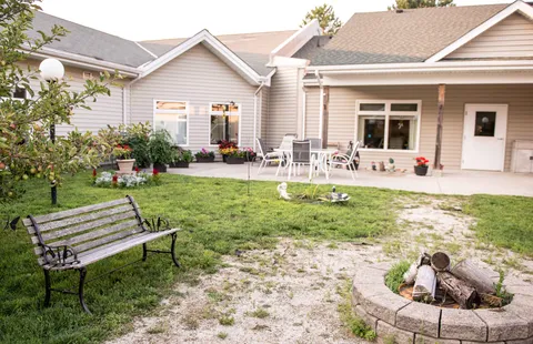 Residence exterior beside a courtyard with benches, patio furniture and a fire pit.