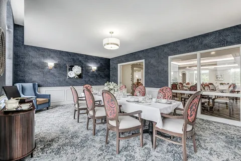 Long dining table with upholstered chairs and floral wall art