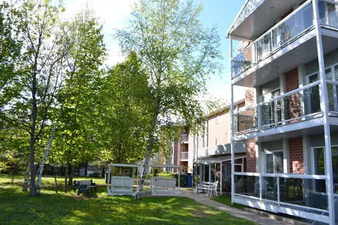 Garden with birch trees, covered swings and balconies along the residence.