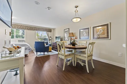 Studio room with a bed, blue armchairs and a round dining table