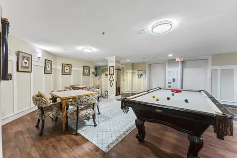 Games room with a billiards table, card tables and upholstered chairs