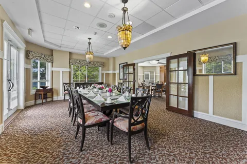 Dining room with a long table, upholstered chairs and stained-glass pendant lights