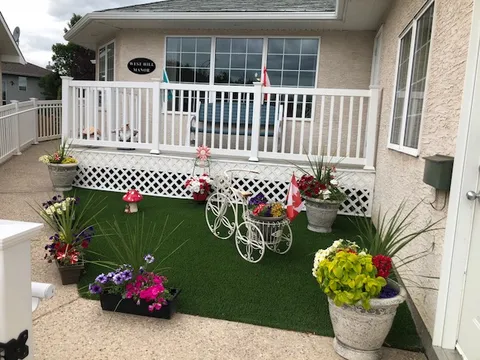 Front porch with railings, flower pots and a residence sign.