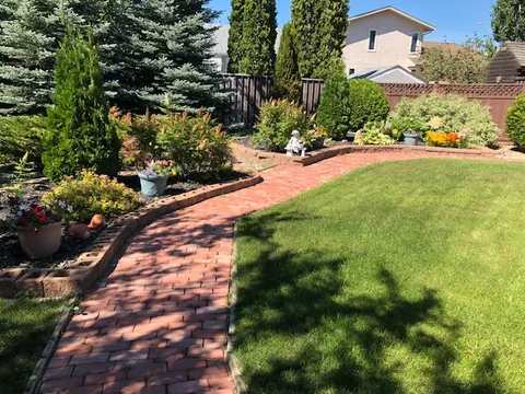 Garden with a curved brick path, lawn and planted borders.