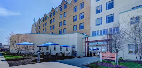Residence exterior with a covered entrance and patio tables with blue umbrellas.