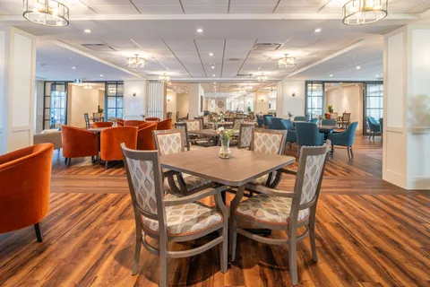 Dining room with tables and chairs on a wooden floor.