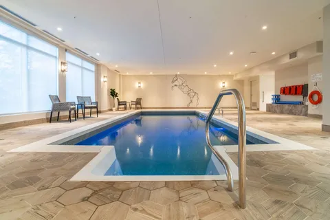 Indoor swimming pool with tiled surrounds and handrails.