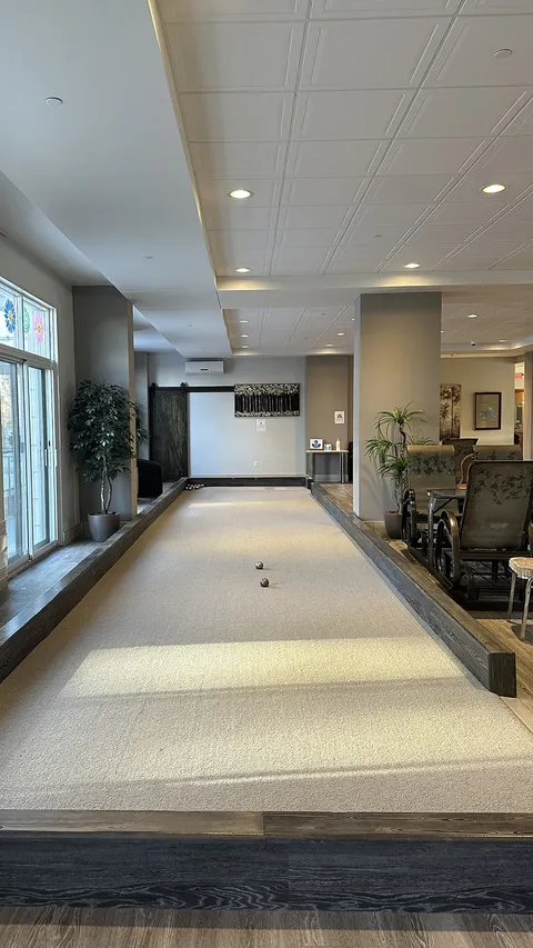 Indoor game court with gravel lanes beside large windows.