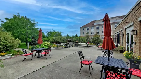 Patio with red chairs and umbrellas beside the residence and garden