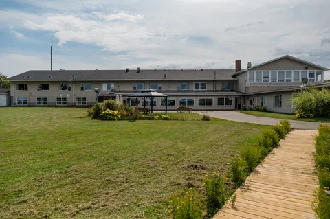 Rear of a low-rise building beside a lawn and wooden garden path