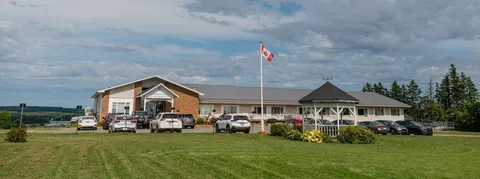Low-rise building with a covered entrance, parked vehicles, a flagpole and lawns