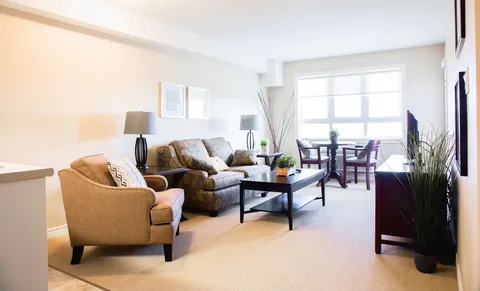 Sitting area with armchairs, a sofa, coffee table and a dining table beside windows