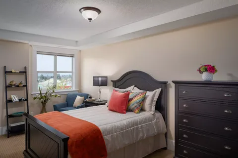 Bedroom with a double bed, dark dresser and blue armchair