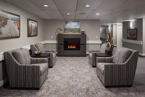 Room with patterned armchairs, a fireplace and landscape paintings