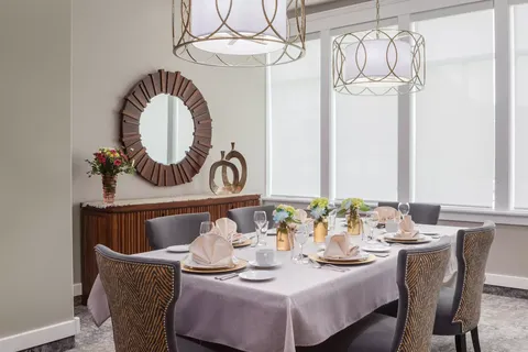 Dining room with a set table, chairs, mirror and large windows