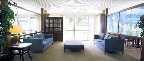 Room with blue sofas, an ottoman and glass doors
