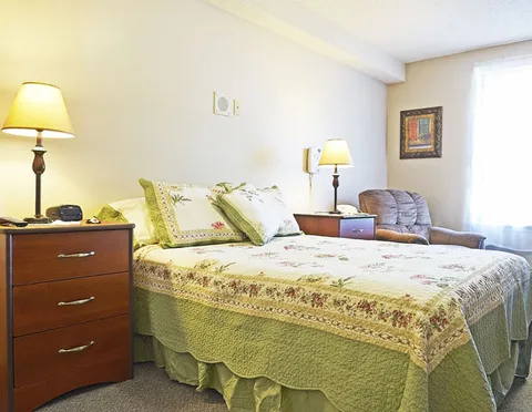 Suite with a double bed, armchair, bedside lamps and window.