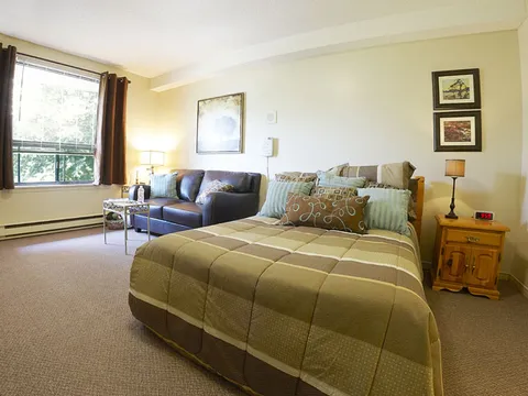 Suite with a bed, sofa, bedside table and window.