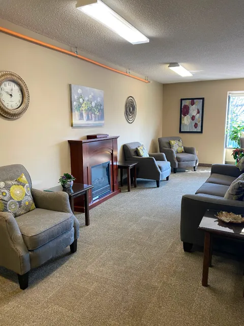 Sitting room with armchairs, a sofa, fireplace and floral wall art.