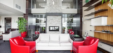 Lounge with a white sofa, red armchairs and a tall stone fireplace