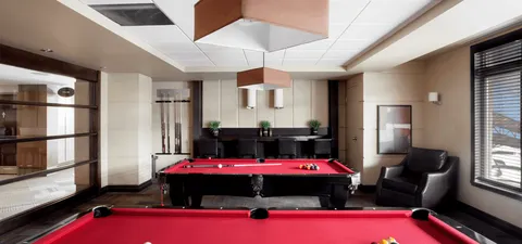 Billiards room with red tables, dark chairs and pendant lights