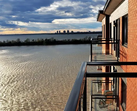 Brick building balconies overlooking a broad river at sunset