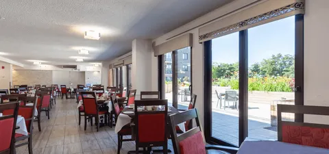 Dining room with red chairs and tables beside large windows