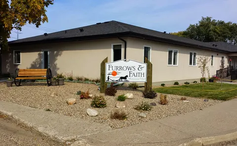 Single-storey residence with a gravel garden, bench and sign.