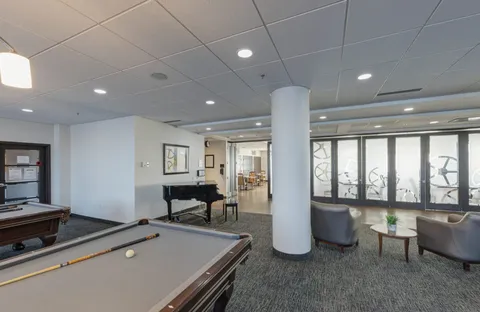 Billiard table beside a grand piano, glass doors and armchairs