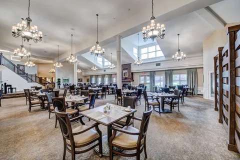 Dining room with tables, chairs, chandeliers and tall windows.