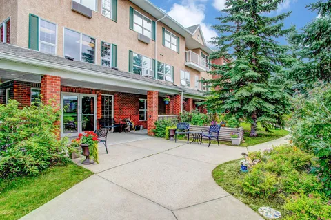 Residence building beside a paved patio and planted beds.