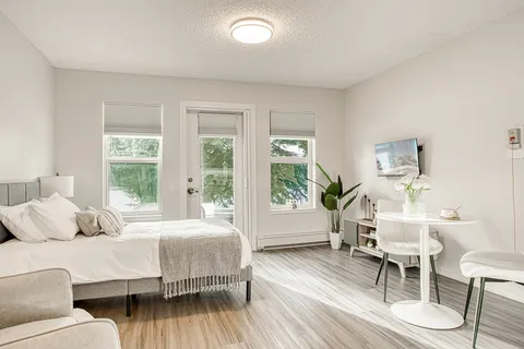 Studio suite with a bed, seating and large windows.