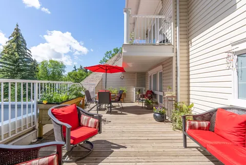 Wooden balcony with red-cushioned chairs and an umbrella