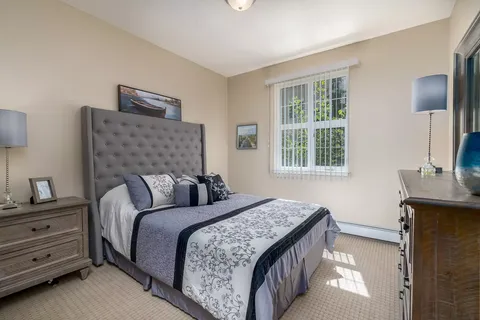 Bedroom with a padded headboard, dressers and a large window