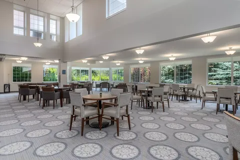 Large room with round tables, chairs and tall windows