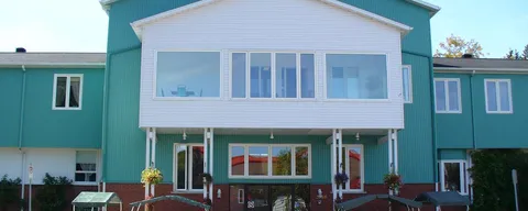 Front exterior with teal siding, white trim and a raised entrance.