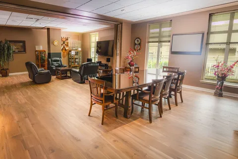 Common lounge with armchairs, tables and wide windows.