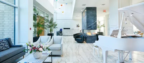 Sofas and armchairs beside a white grand piano and a fireplace