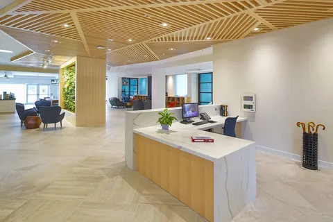 Lobby reception desk beneath a ceiling with wooden slats.