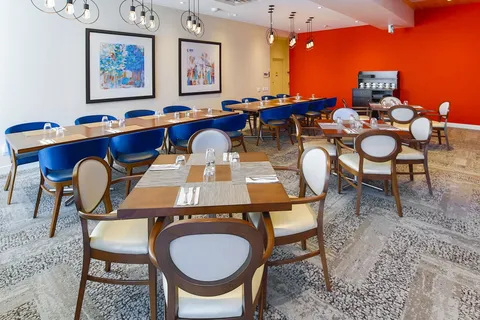 Dining room with tables, chairs and a coffee machine beside a red wall.