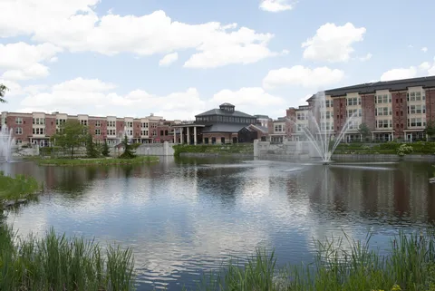 Residence buildings across a pond with a fountain and reeds