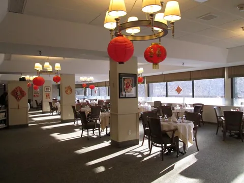 Dining room with set tables and red hanging lanterns.