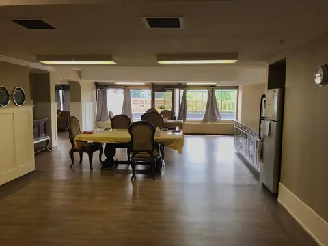 Room with dining tables, upholstered chairs, windows and a refrigerator