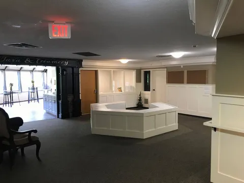 Carpeted area with a central white bench and wide openings to adjoining rooms