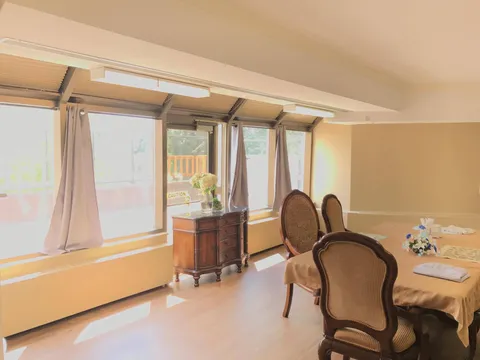Dining table with upholstered chairs, a flower vase and a row of windows