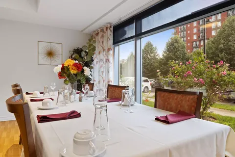 Set dining table beside large windows and flowering shrubs