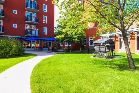 Brick residence buildings around a courtyard with lawn and a paved path
